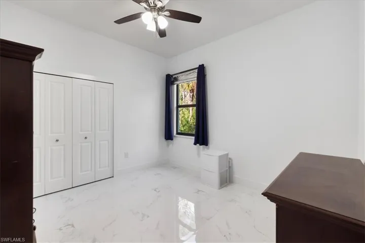 Unfurnished bedroom with baseboards, ceiling fan, a closet, and marble finish floor