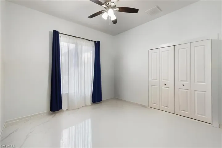 Unfurnished bedroom featuring visible vents, ceiling fan, and a closet