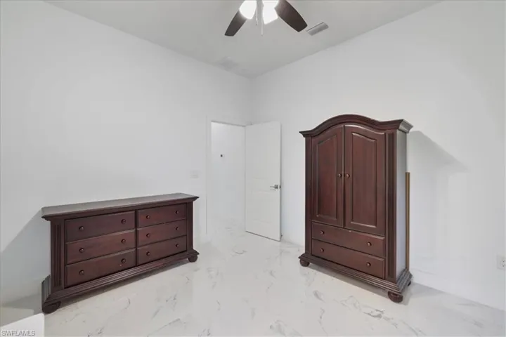Unfurnished bedroom with visible vents, ceiling fan, and marble finish floor