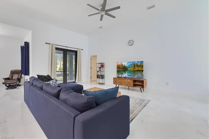 Living room featuring ceiling fan, visible vents, baseboards, a towering ceiling, and marble finish floor