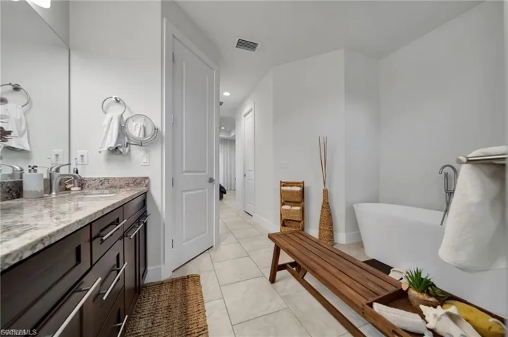 Bathroom with a soaking tub, vanity, recessed lighting, and light tile patterned flooring