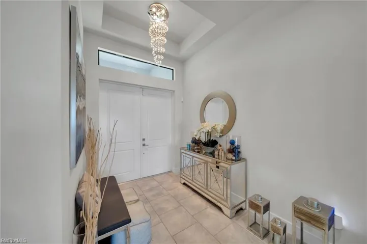 Entryway with light tile patterned floors, a raised ceiling, and suspended lighting
