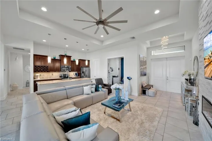 Living area with ceiling fan, a tray ceiling, a chandelier, and light tile patterned floors