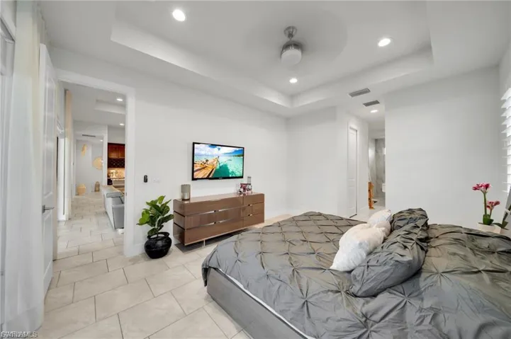 Bedroom with recessed lighting, a tray ceiling, light tile patterned floors, and a ceiling fan