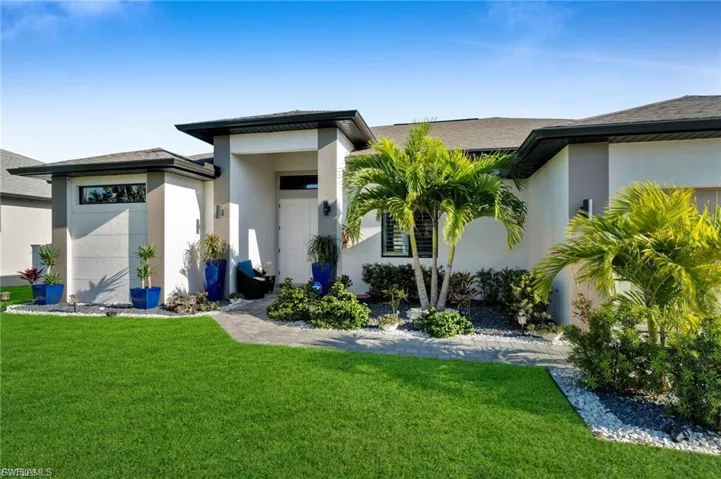 Back of property with a lawn, stucco siding, and roof with shingles