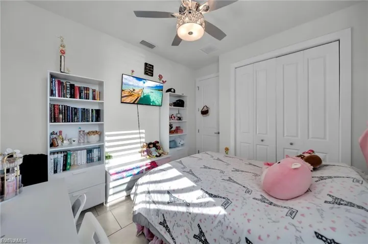 Bedroom featuring ceiling fan, light tile patterned floors, and a closet