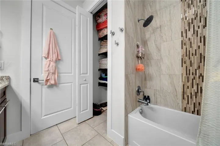 Bathroom with shower / bath combination, vanity, and light tile patterned floors