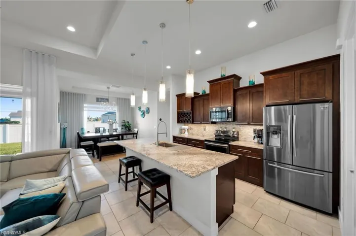 Kitchen with stainless steel appliances, a breakfast bar area, open floor plan, and dark wood finish cabinets
