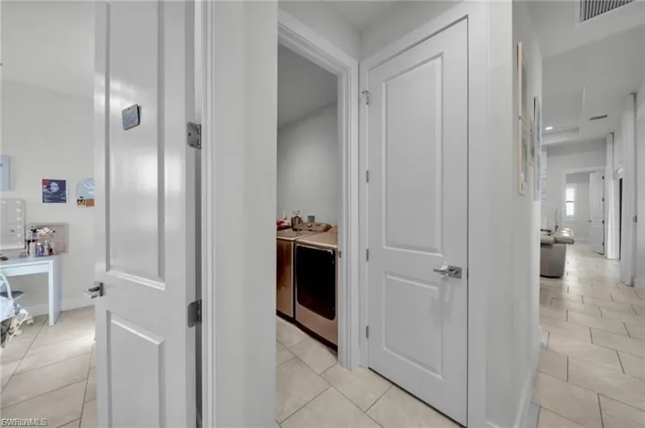 Hallway with independent washer and dryer, light tile patterned floors, and recessed lighting