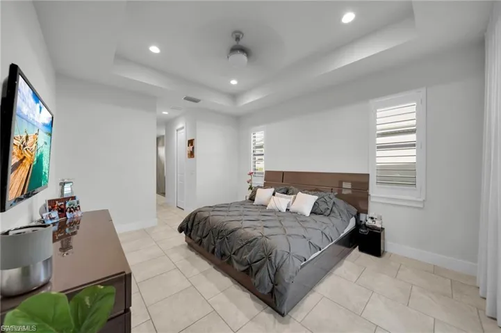 Bedroom featuring recessed lighting, a tray ceiling, and light tile patterned floors