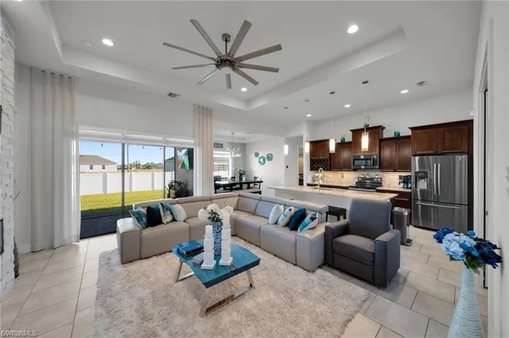 Living area with a ceiling fan, recessed lighting, a raised ceiling, and light tile patterned floors