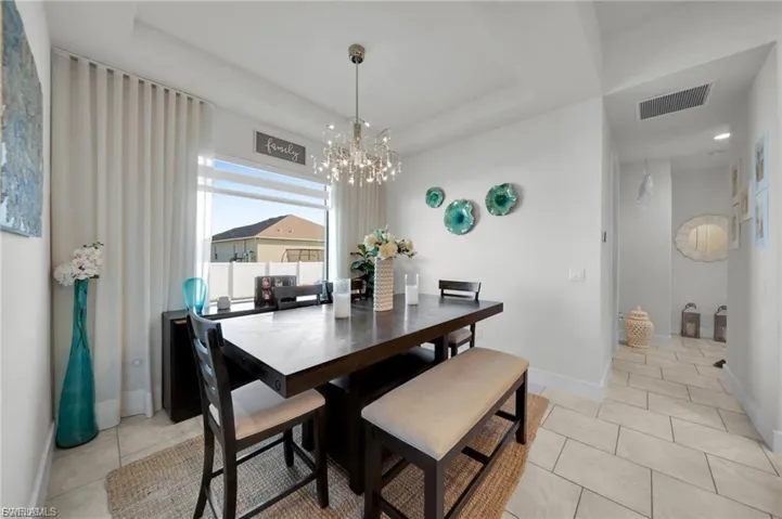 Dining space with a chandelier, a tray ceiling, and light tile patterned floors