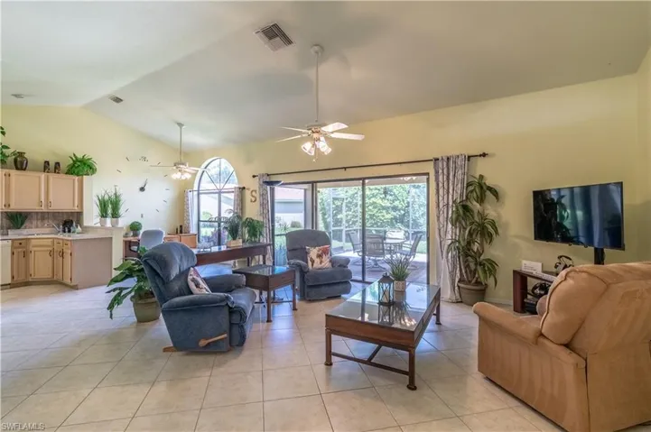 Living room featuring high vaulted ceiling, ceiling fan, and light tile patterned floors