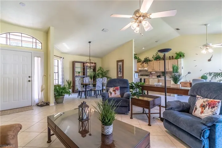 Living room with lofted ceiling, ceiling fan, and light tile patterned floors