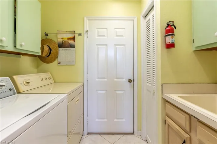 Laundry room with cabinets, washing machine and dryer, and light tile patterned flooring