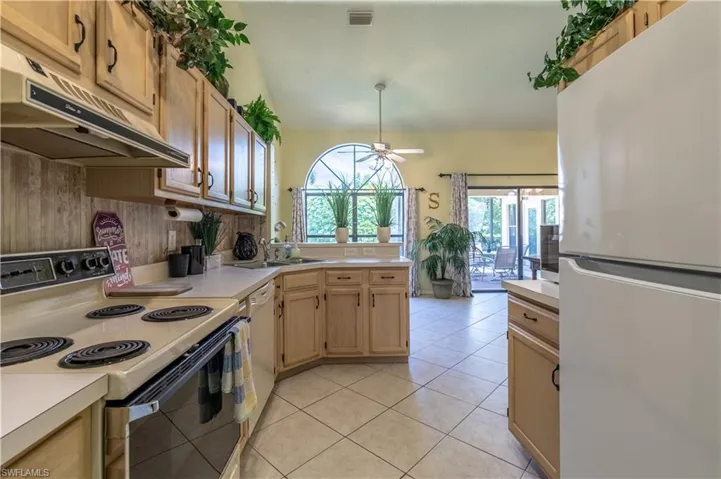 Kitchen featuring white appliances, light tile patterned floors, tasteful backsplash, light brown cabinets, and ceiling fan
