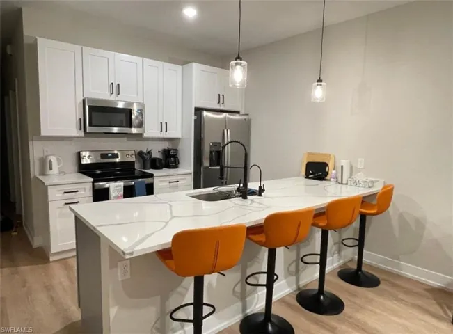 Kitchen with a breakfast bar area, a peninsula, stainless steel appliances, and white cabinets