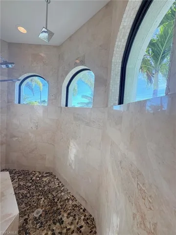PRIMARY BATHROOM'S WALK THROUGH SHOWER WITH 3 SHOWER HEADS, BENCH
