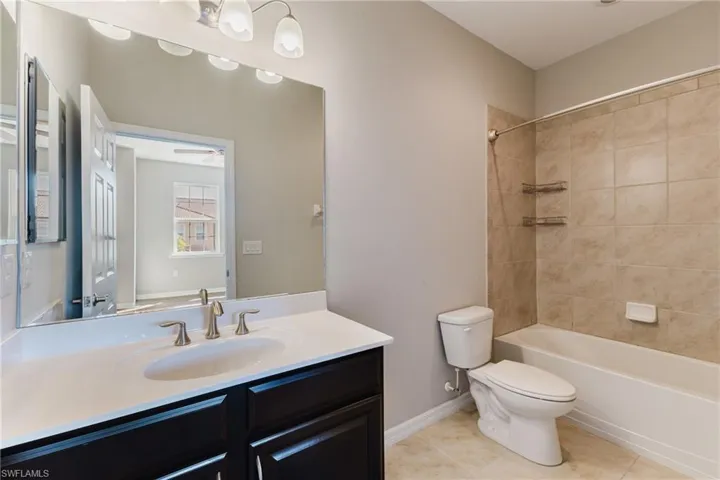 Bathroom with vanity, shower / washtub combination, and light tile patterned flooring