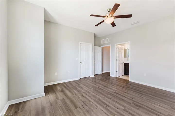 Unfurnished bedroom with light wood finished floors, ceiling fan, and connected bathroom