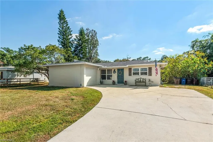 Single story home featuring a garage, concrete driveway, and stucco siding