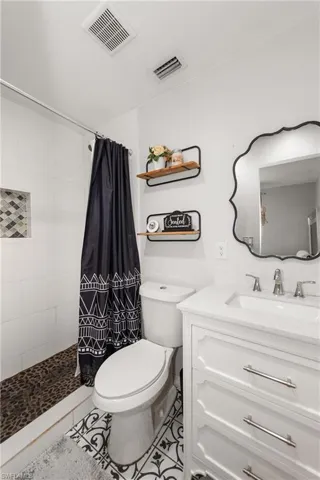 Bathroom with vanity, a tile shower, and light tile patterned floors