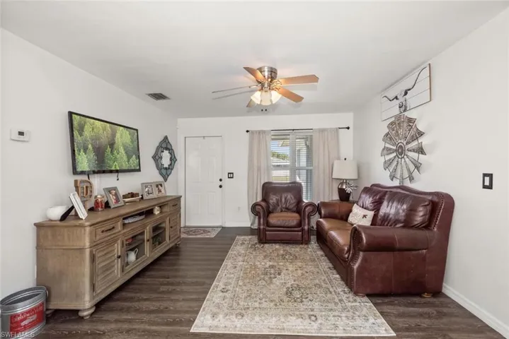 Living area featuring a ceiling fan and dark wood-style floors