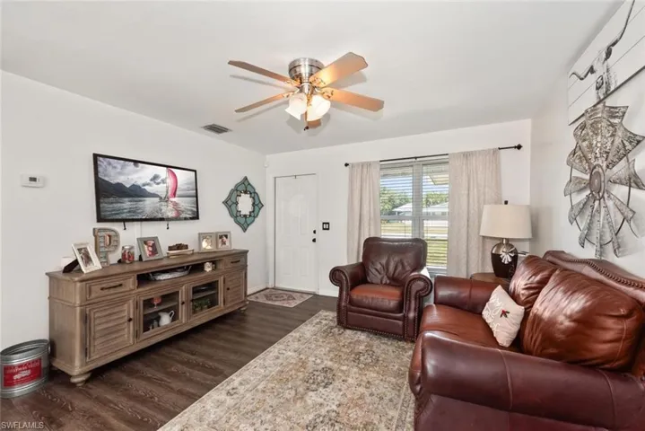 Living room with dark wood-type flooring and ceiling fan
