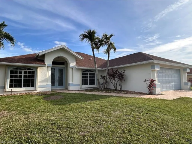 Contemporary single-story residence featuring a clean stucco exterior with arched entryway, multiple large windows with decorative trim, and a two-car garage
