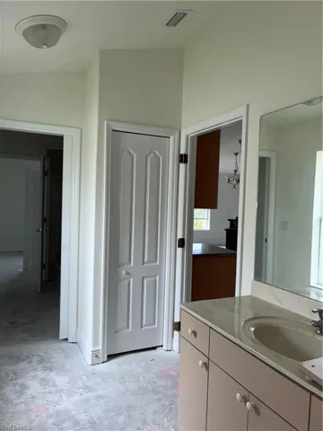 Spacious primary bathroom featuring dual vanity with ample counter space, large framed mirror, ceramic sink, and wood-finish cabinetry