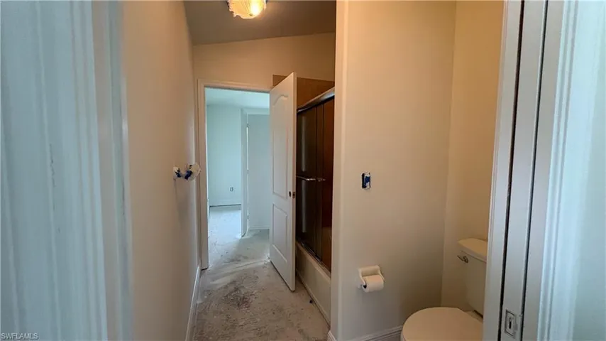 Full bathroom featuring a tub with sliding glass shower doors and a white commode