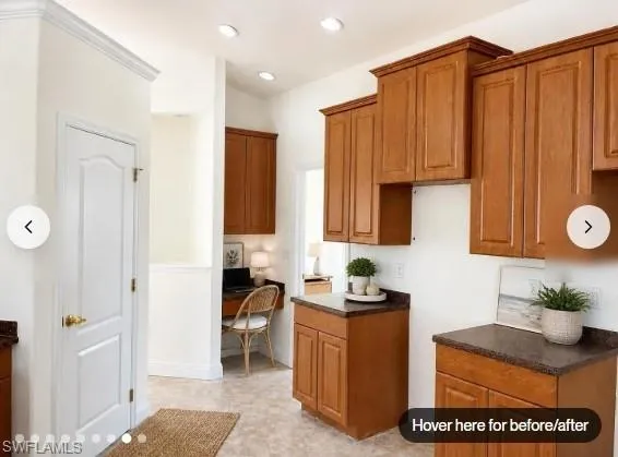 Staged Wood-finish cabinetry with crown molding, dark countertops, recessed lighting, and a built-in desk area