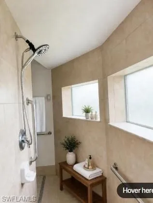 Staged Tiled shower enclosure featuring a multi-function shower head, grab bars, and two frosted windows