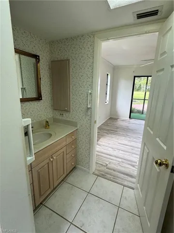 Bathroom with vanity, light tile patterned flooring, and wallpapered walls