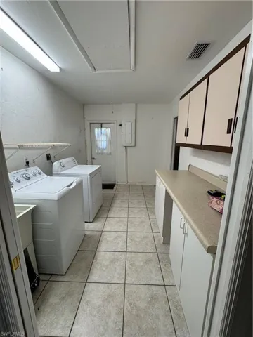 Laundry room with attic access, cabinet space, light tile patterned floors, and independent washer and dryer. This used to be garage area converted into living.  Electic panel and a storage area.