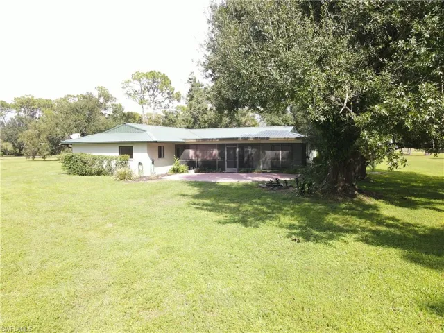 Rear view of house featuring a lawn, a sunroom, and a metal roof