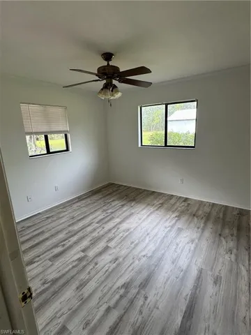 Unfurnished bedroom 2 with light wood look laminate finished floors, ornamental molding, and a ceiling fan and a walk in closet