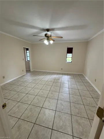 Spare room with light tile patterned flooring, ornamental molding, a ceiling fan and small walk-in closet.  This used to be the garage.  Room can be used for whatever purpose a buyer wants, bedroom, mancave, game room, home office, etc...