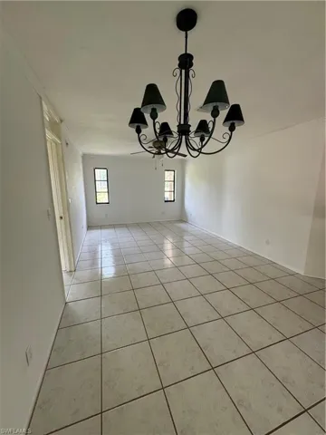 Unfurnished dining area with a chandelier, light tile patterned floors, and crown molding