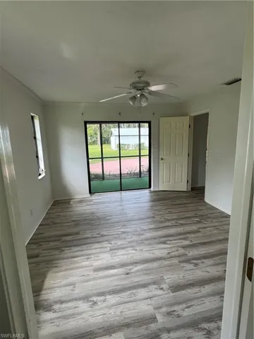 looking at Primary bedroom from bathroom with light gray vinyl floors, crown molding, and ceiling fan