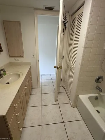 Full bath featuring a closet, vanity, light tile patterned floors, and shower / tub combination