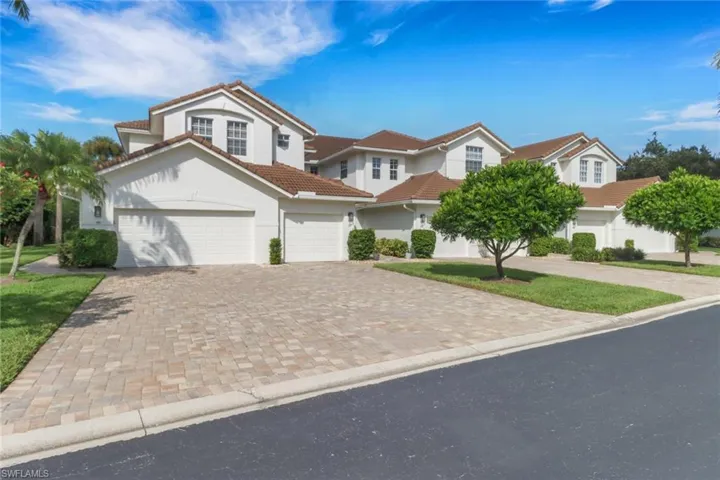 View of front of property with stucco siding, a tiled roof, decorative driveway, and an attached garage