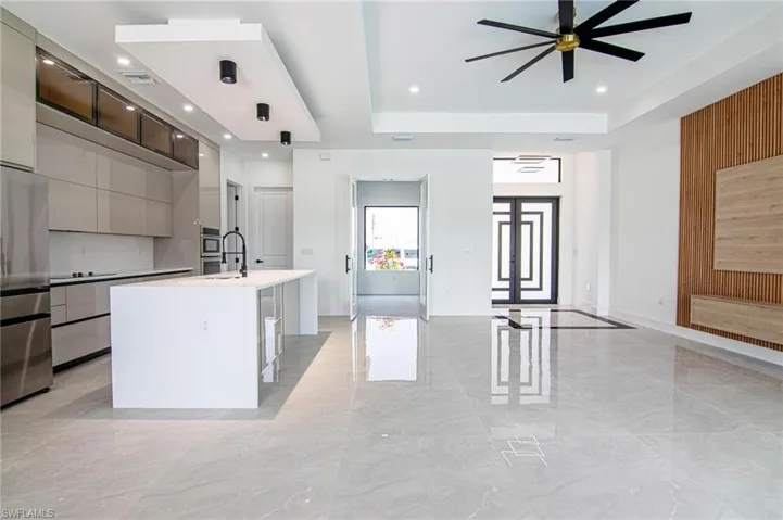 Kitchen with modern cabinets, open floor plan, appliances with stainless steel finishes, a raised ceiling, and a ceiling fan