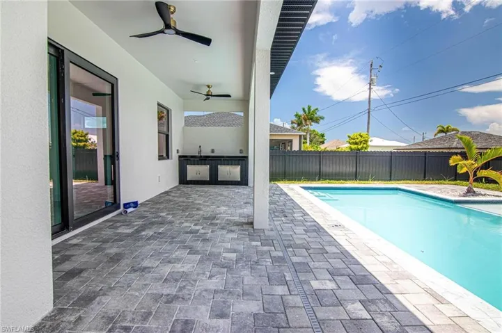 View of pool with exterior kitchen, a fenced backyard, ceiling fan, and a patio area
