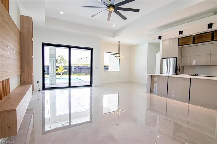 Unfurnished living room with a chandelier, a raised ceiling, a ceiling fan, and recessed lighting