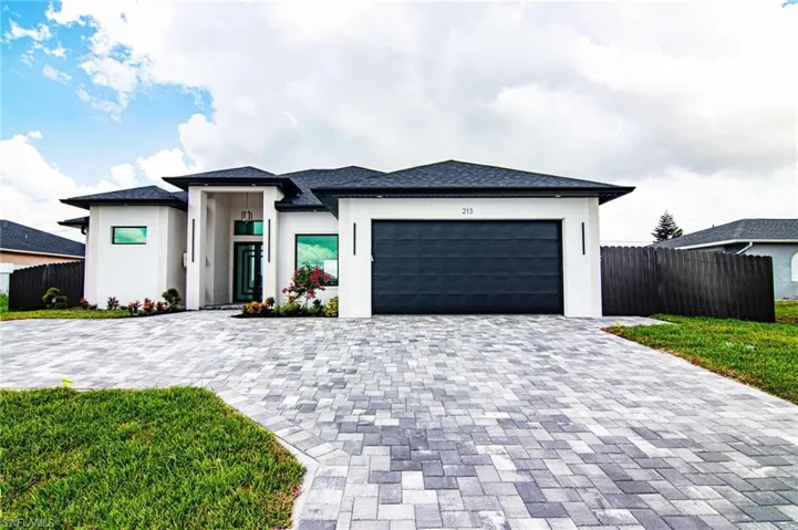 Prairie-style home with a garage, decorative driveway, and stucco siding