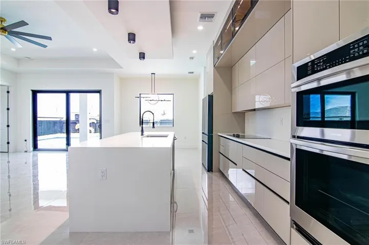 Kitchen with modern cabinets, appliances with stainless steel finishes, a center island with sink, light countertops, and recessed lighting