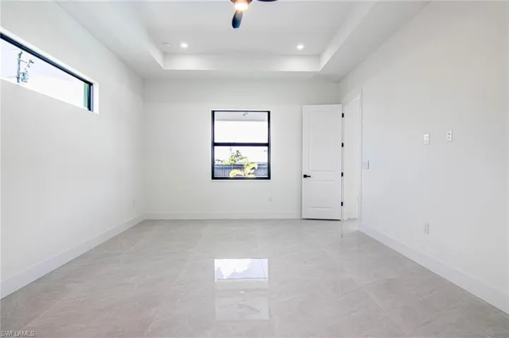 Empty room with a raised ceiling, a ceiling fan, and recessed lighting