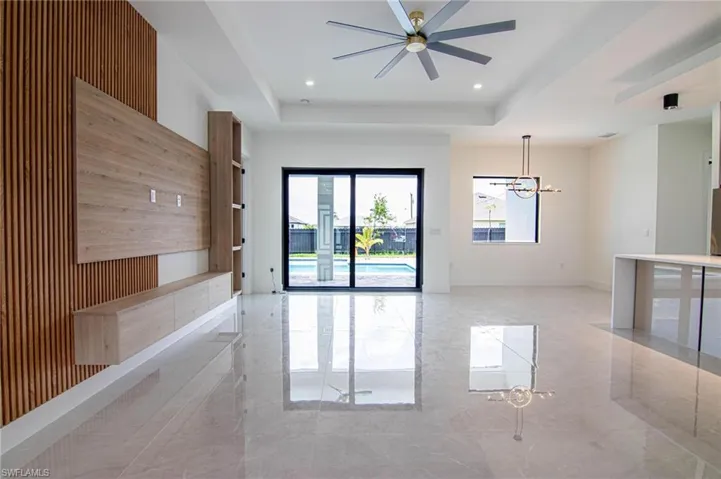 Unfurnished room with a chandelier, a raised ceiling, ceiling fan, marble tiled floors, and wood walls