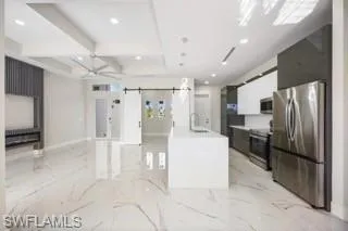 Kitchen featuring hanging light fixtures, stainless steel appliances, a barn door, sink, and light tile flooring